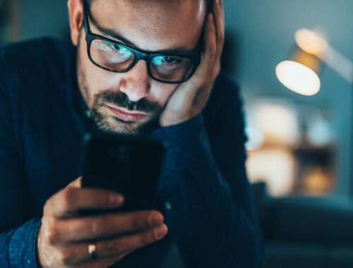 Man looking down at phone reading.