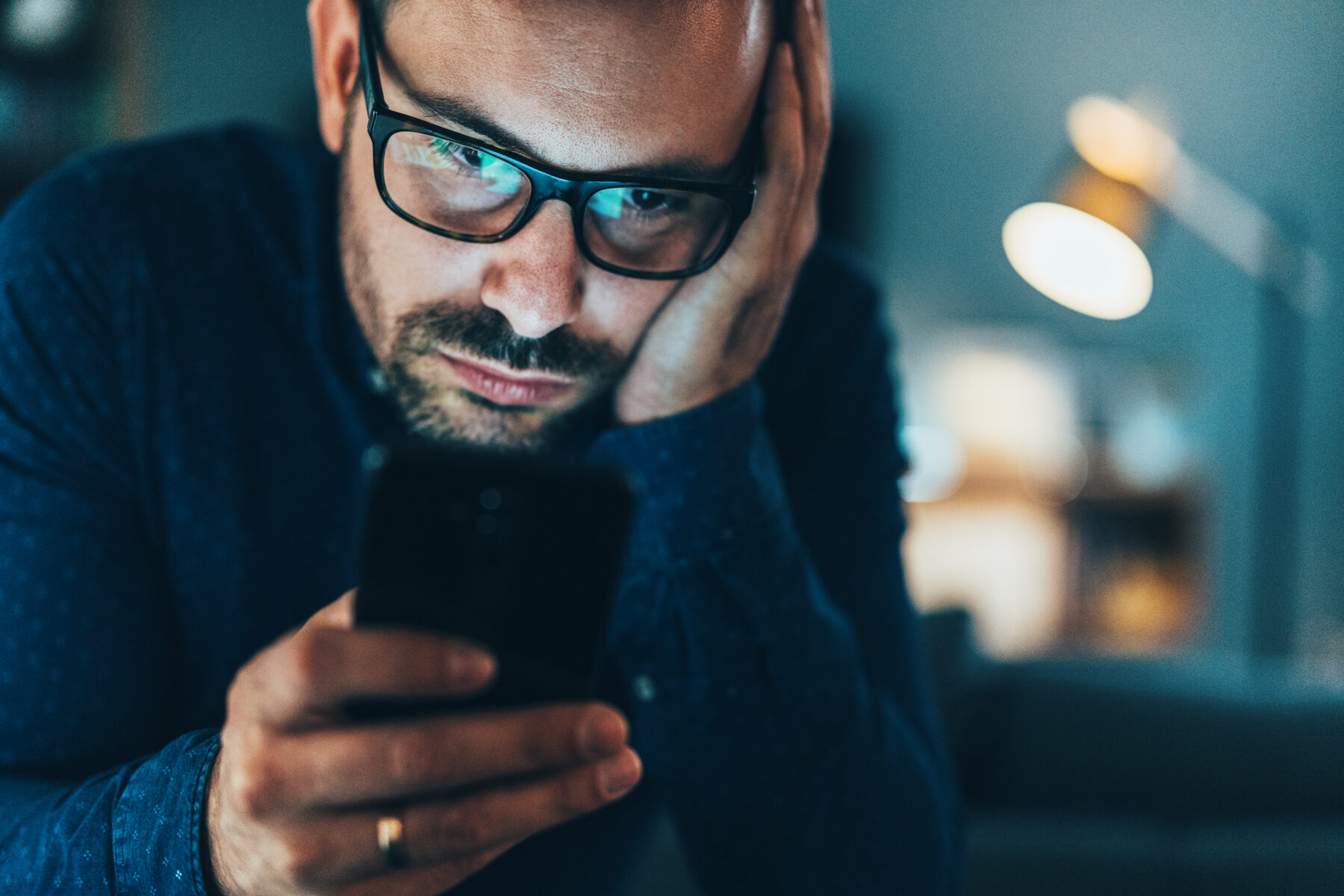 Man looking down at phone reading.