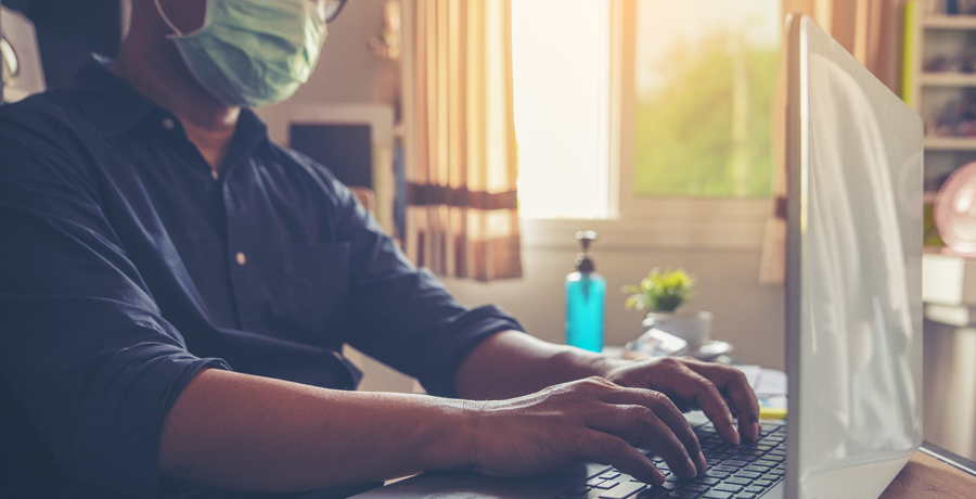 person wearing mask on computer