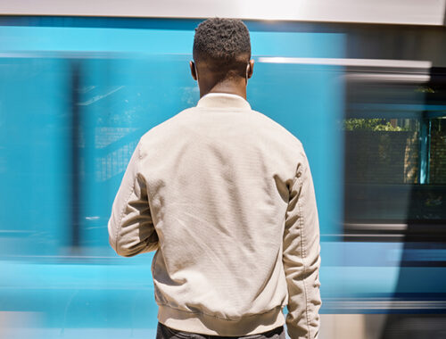 Black man facing away from the camera, waiting for public transportation
