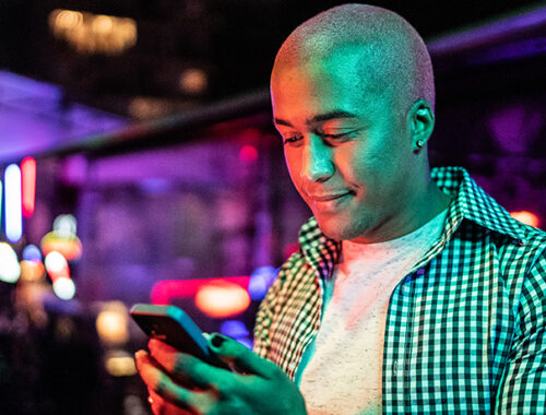 Man looking down at phone inside a club.