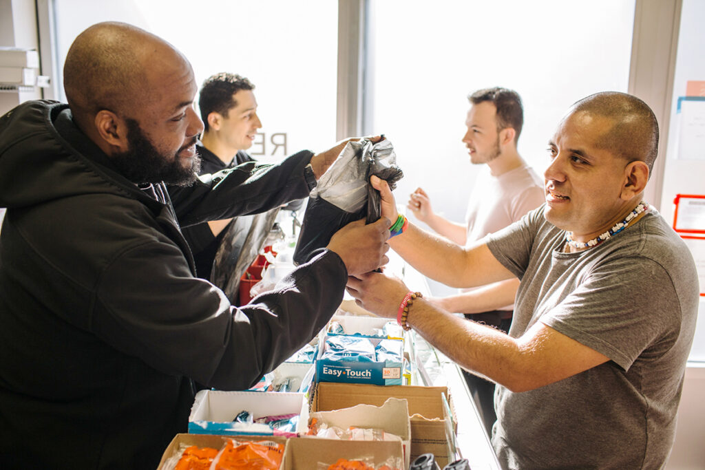 An image of two people providing harm reduction supplies to two people.