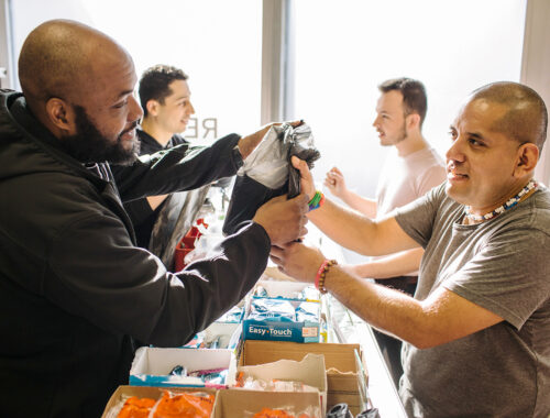 An image of two people providing harm reduction supplies to two people.