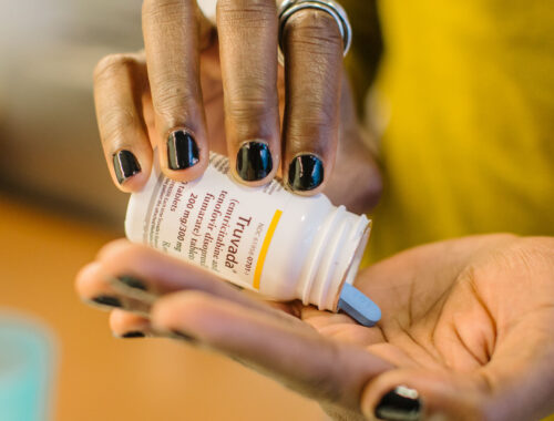 A person dispenses a blue pill from a medication bottle into their hand