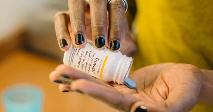 A person dispenses a blue pill from a medication bottle into their hand