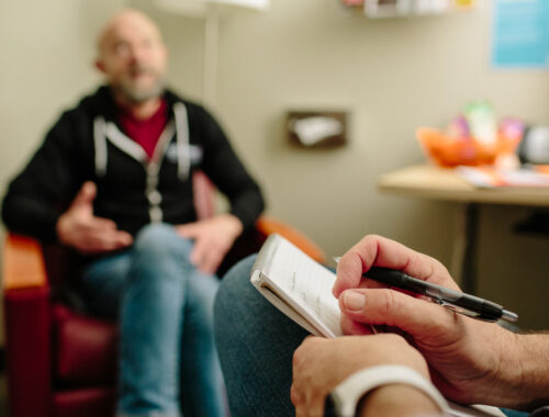 A counselor sitting with a client in a counseling room at SFAF.