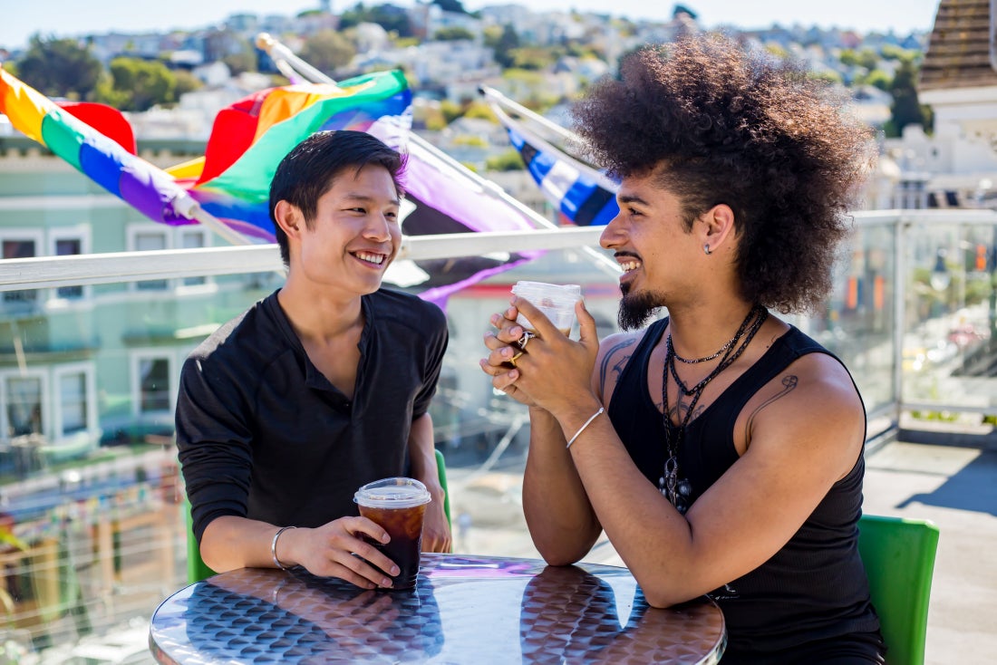 Two people sitting drinking coffee on patio at SFAF health center Strut