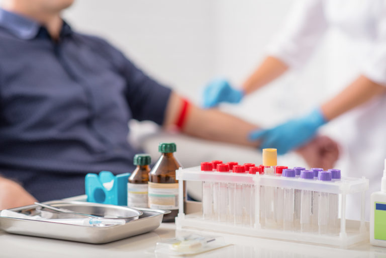 Doctor preparing patient for blood sampling. Focus on blood test tools on table