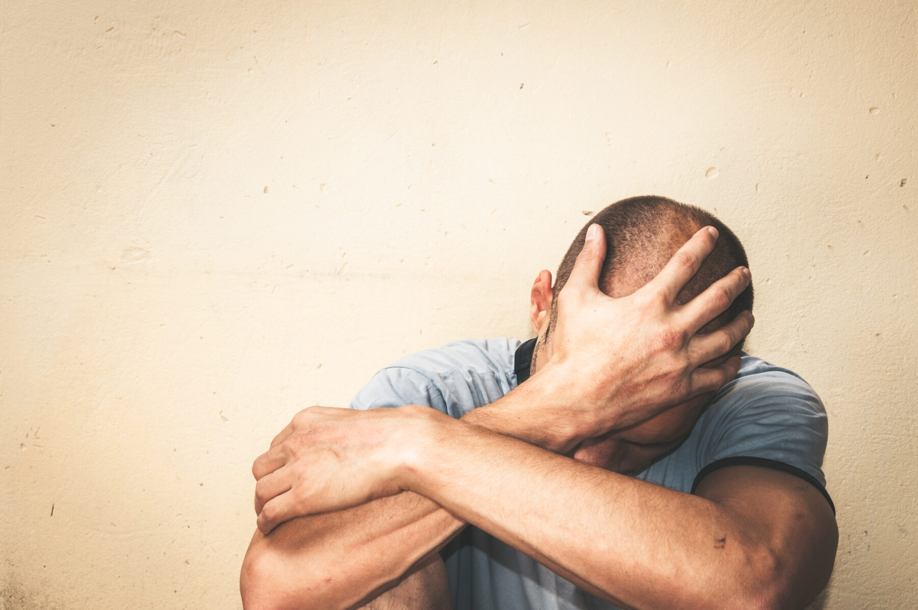 person sitting down and holding their head in their hands