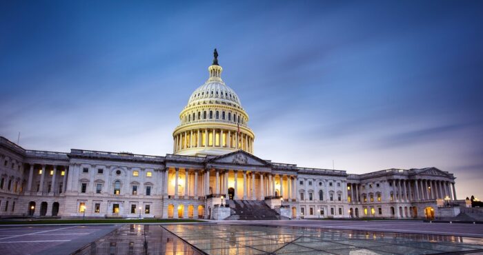 Capitol building in Washington DC illuminated against a stormy sky