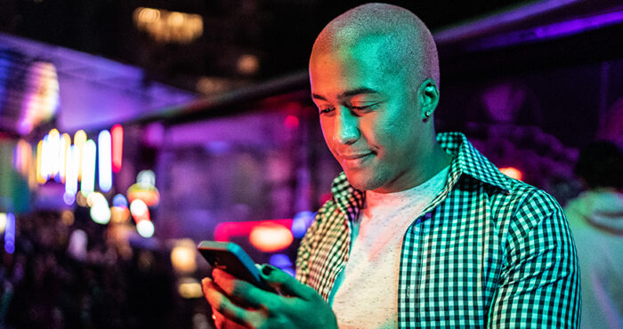 Man looking down at phone inside a club.