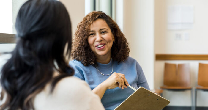 Counseling session with two people seated, the counselor is facing the camera and smiling