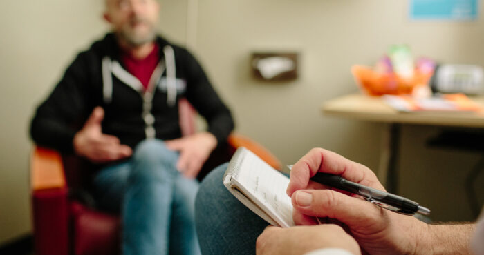 A counselor sitting with a client in a counseling room at SFAF.