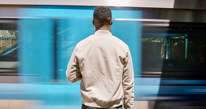 Black man facing away from the camera, waiting for public transportation