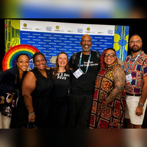Six colleagues standing together in front of the AIDS 2026 Global Village backdrop in Rio de Janeiro