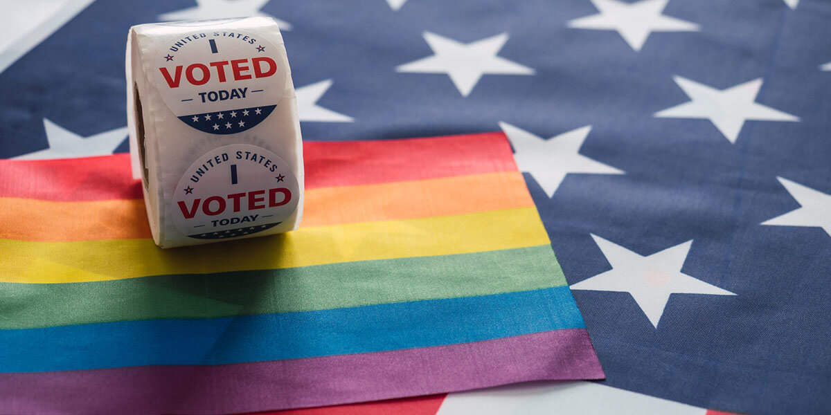 A roll of red, white, and blue "I Voted Today" stickers resting on a rainbow Pride flag laid over an American flag