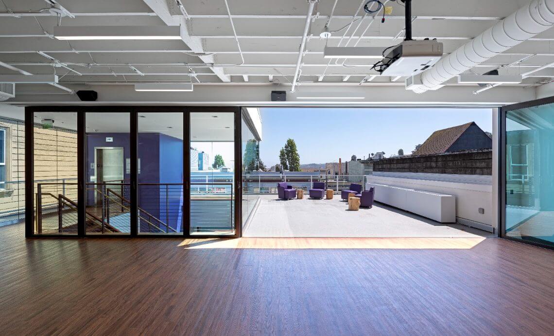 The 3rd floor swing space at Strut, with glass walls looking out to the roof deck.
